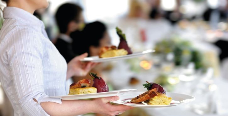 Waitress carrying three plates with meat dish